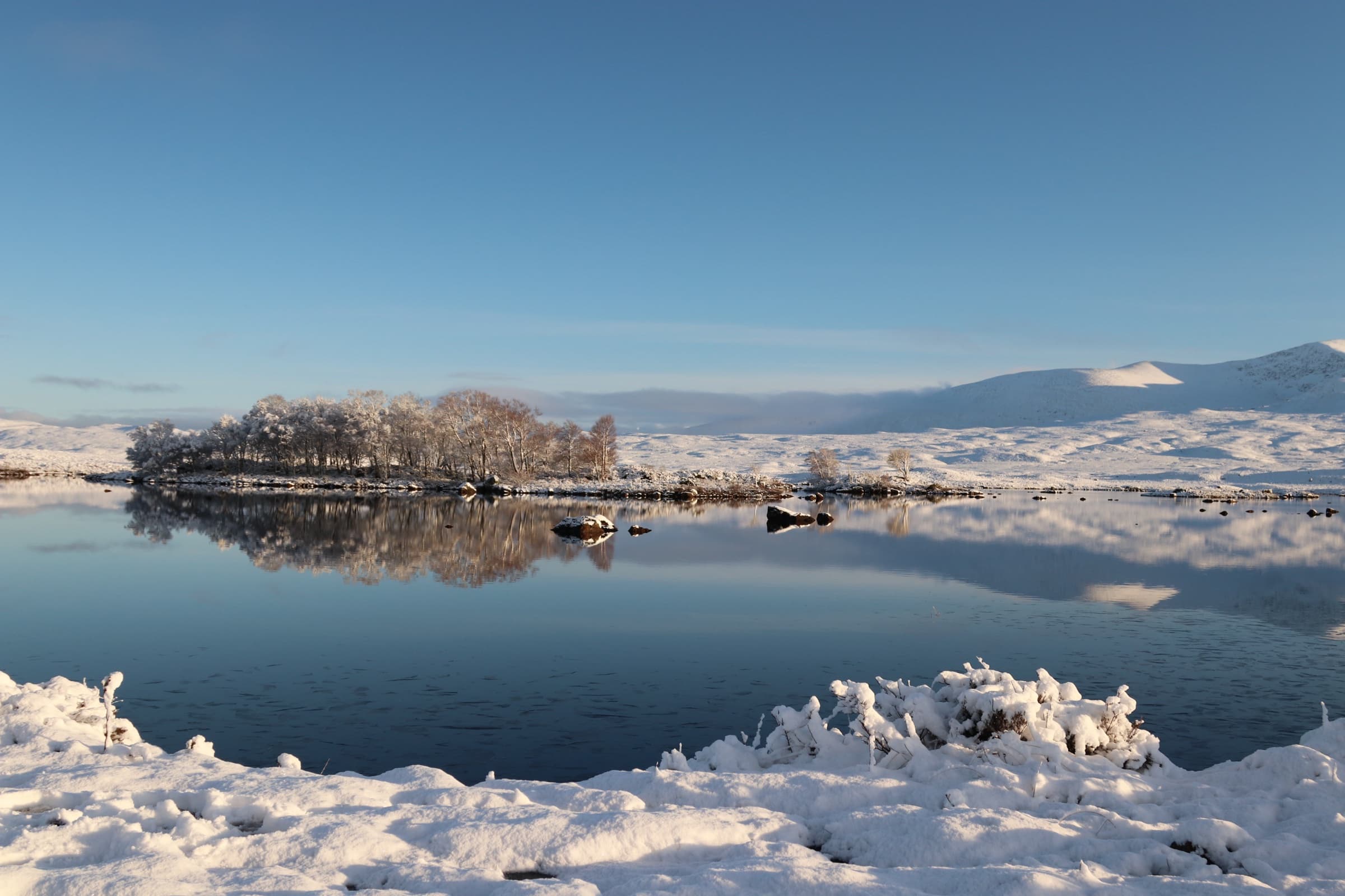 Snow-covered Rannoch Moor reflected in a calm loch